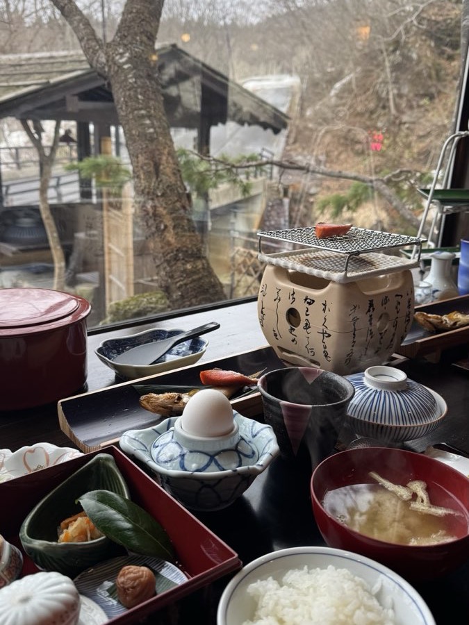 A traditional Japanese breakfast of rice, miso and grilled fish on a charcoal burner, beside a garden window