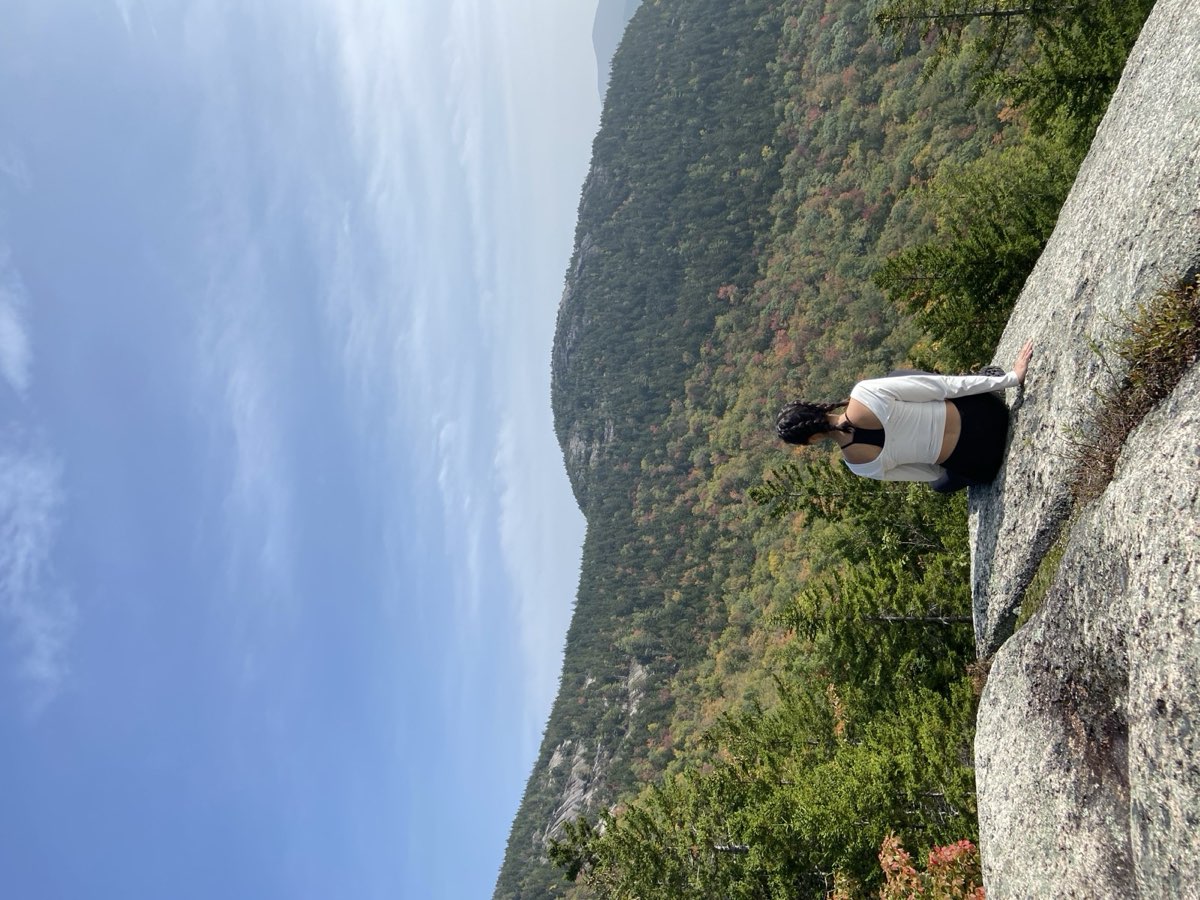 Nikki sitting on a granite ledge looking out over rolling hills turning red and gold